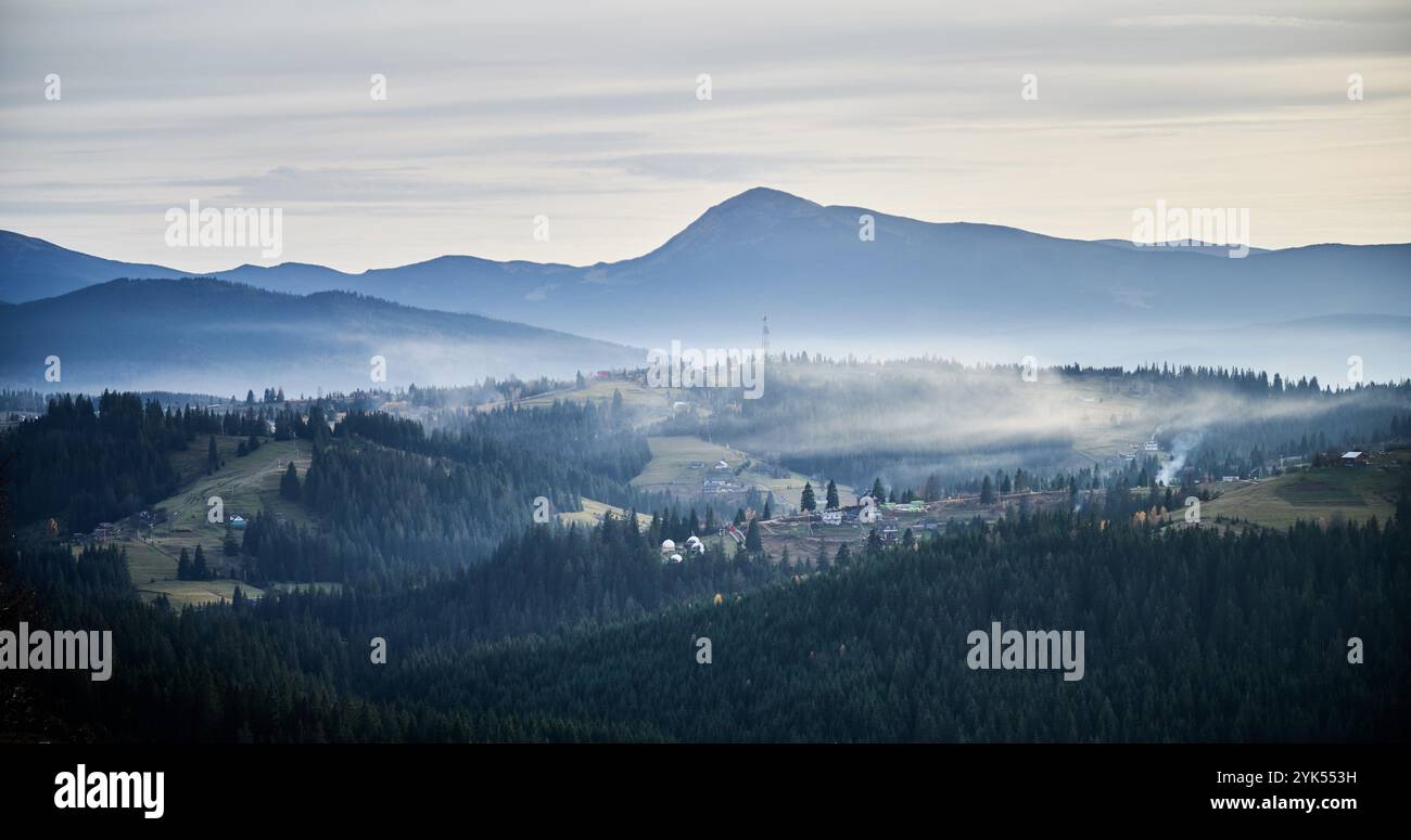 Misty mountain landscape at dawn, with layers of dark green forests and ...