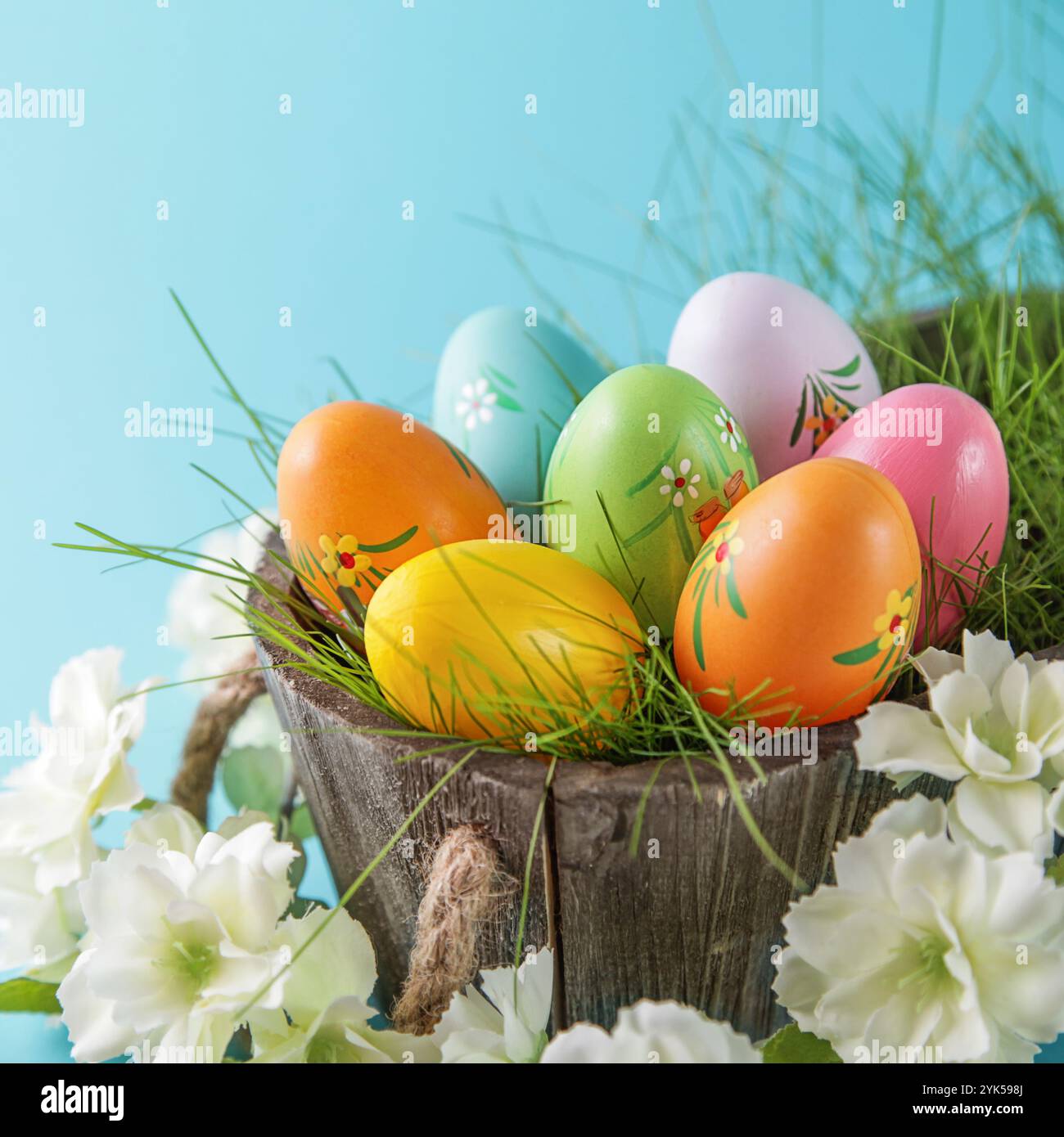 Happy Easter. Colorful Easter eggs and white flower on blue background. Square image Stock Photo