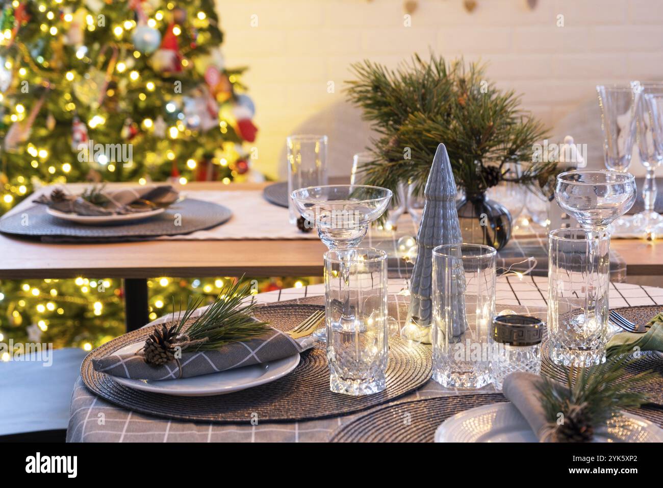 Serving a festive table with plates, forks, knives, napkins, glasses close-up in the modern interior of a loft house decorated for Christmas and New Y Stock Photo