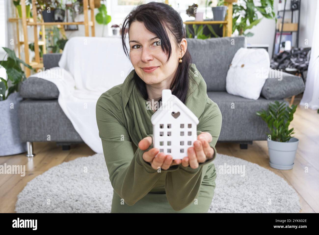 A happy woman in her house holds in her hands a miniature figure of a ...