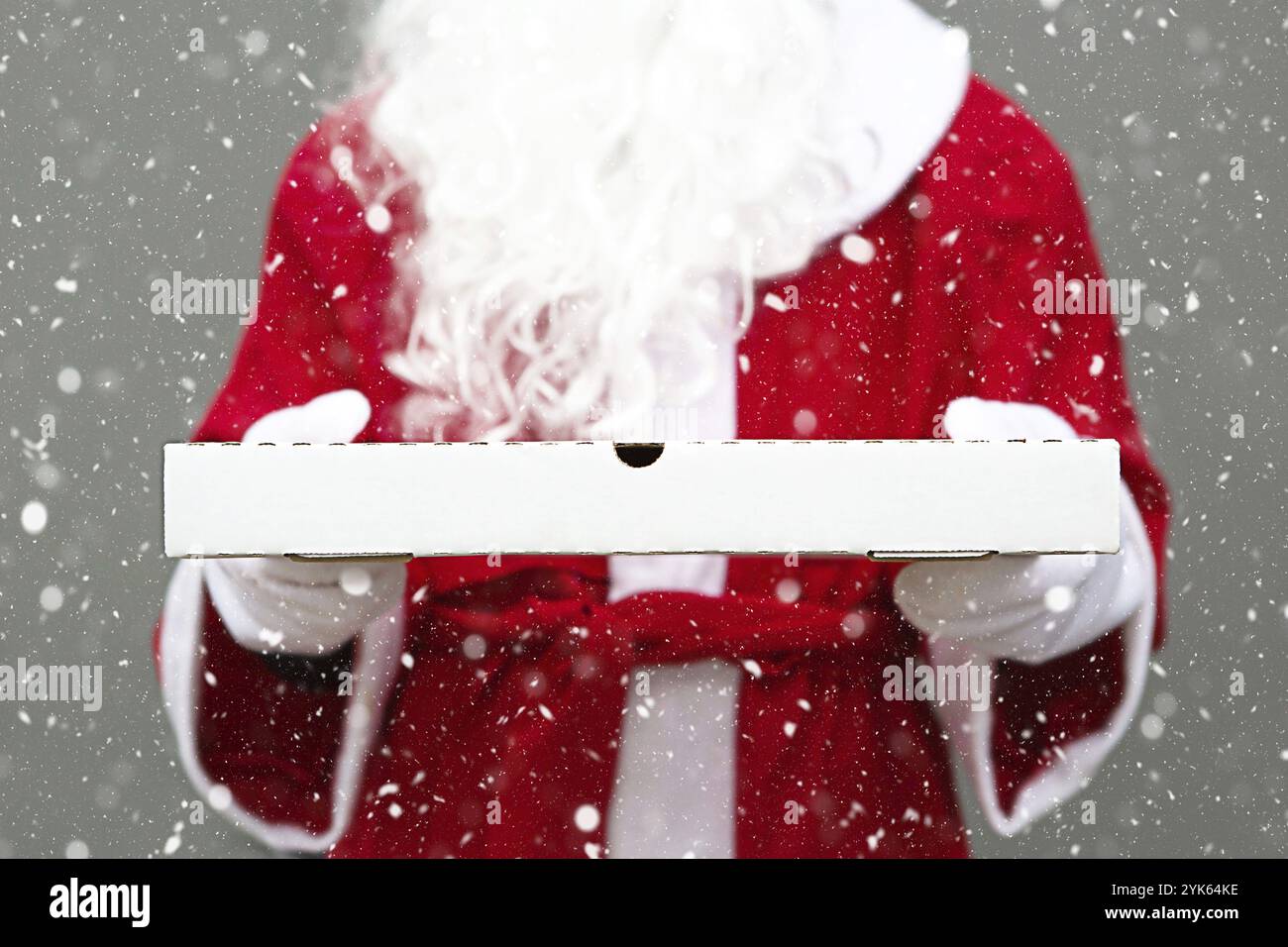 White pizza box in the hands of Santa Claus in white mittens, with a beard, in a red coat. Christmas fast food delivery. New year's eve promotion. Wor Stock Photo