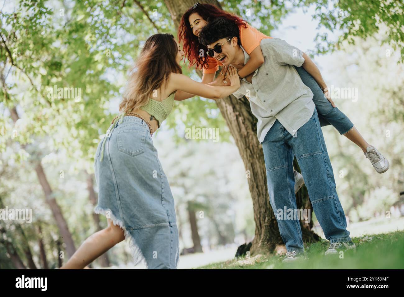 Young friends having fun in the park with piggyback rides on a sunny day Stock Photo