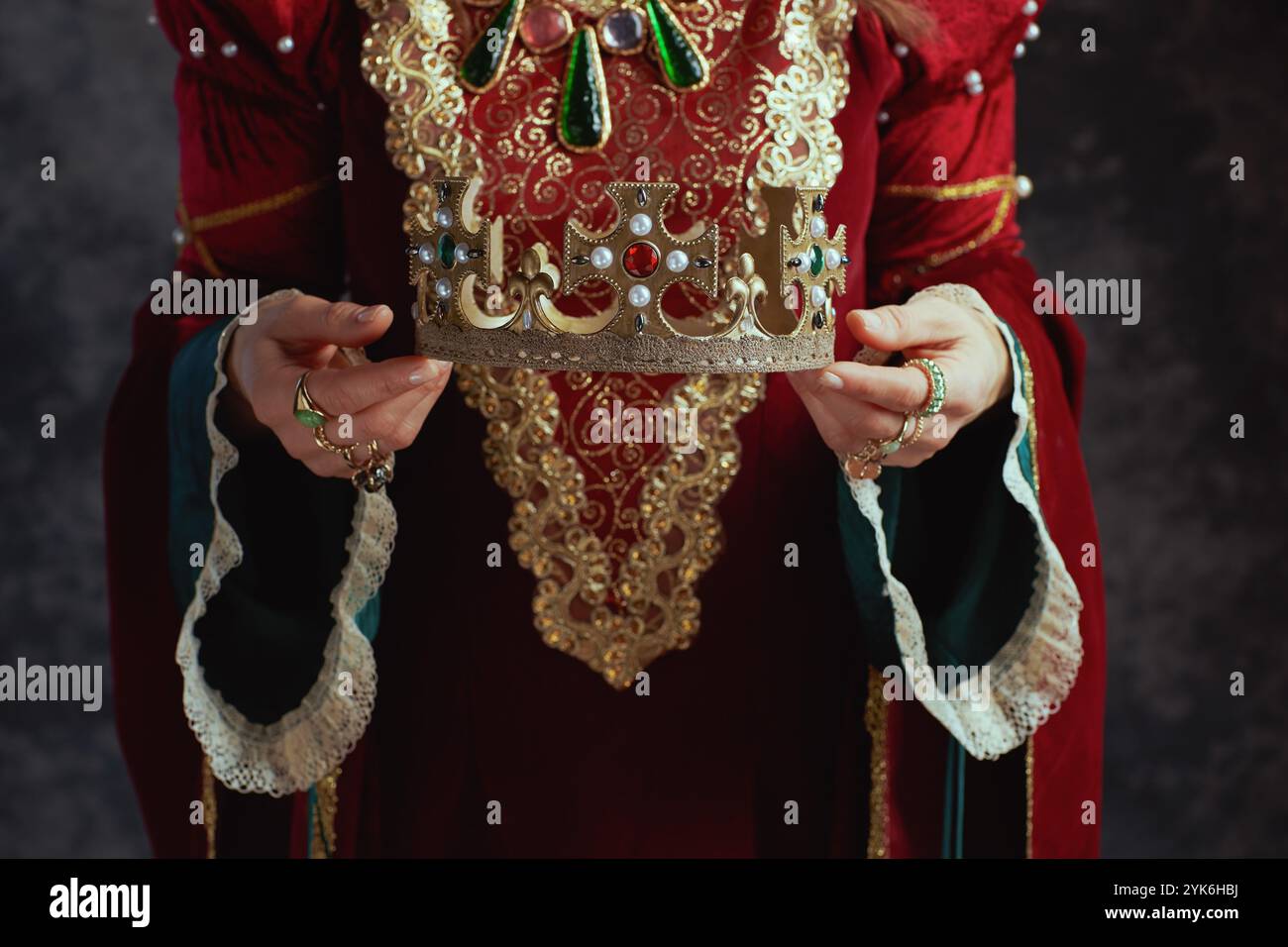 Closeup on medieval queen in red dress with crown on dark gray ...