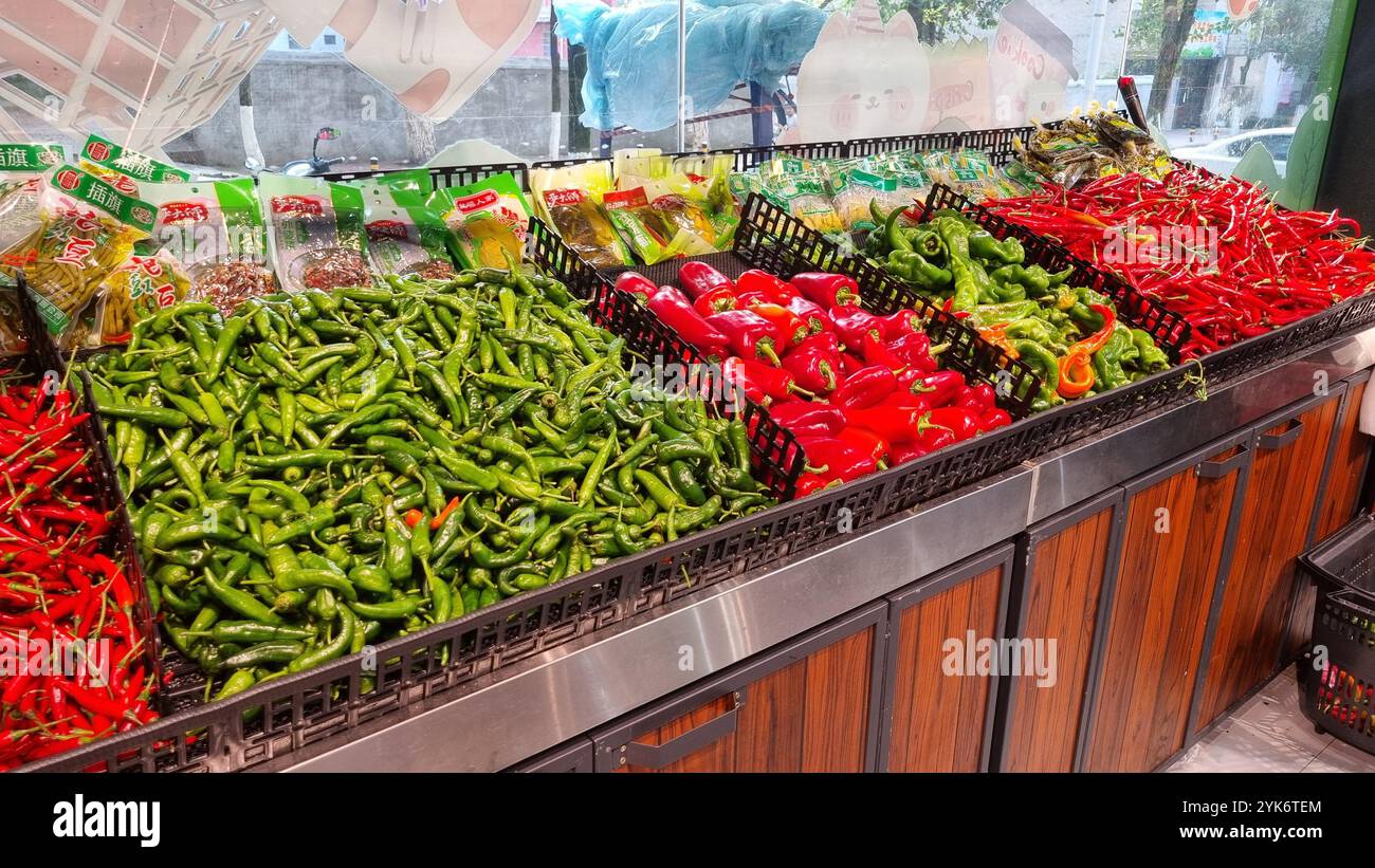 A vibrant display of fresh chili peppers at a supermarket in China. The stand is filled with various types of chili peppers. Stock Photo