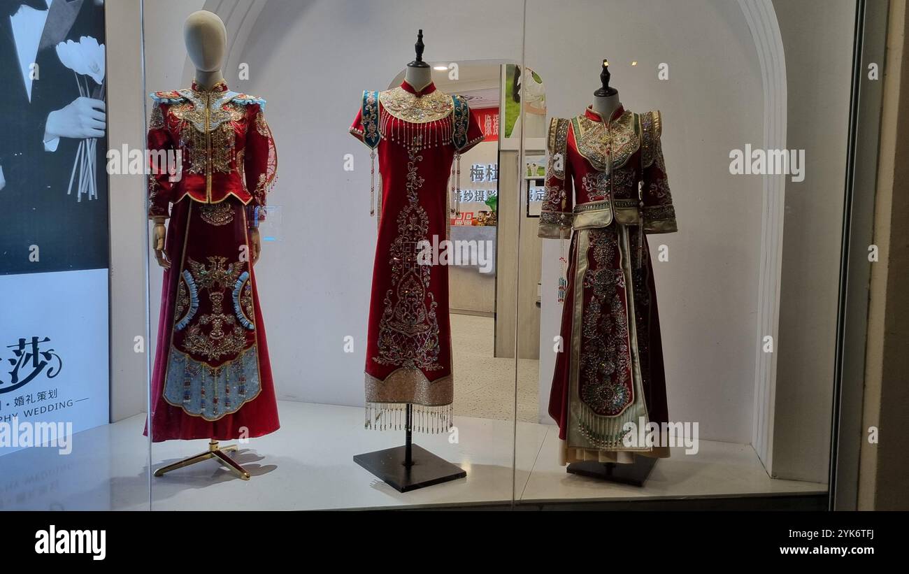 A showcase of three traditional Chinese wedding dresses on mannequins. - Smartphone Captured Stock Image