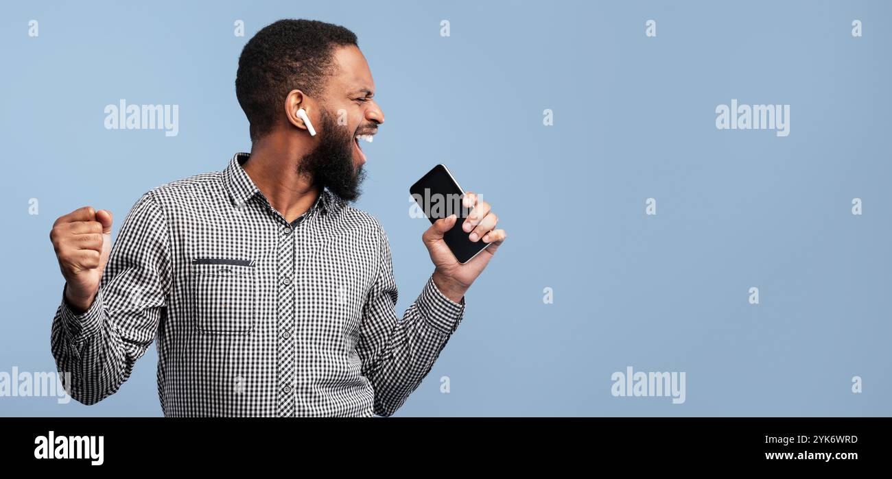 Happy afro man singing using smartphone as mic Stock Photo