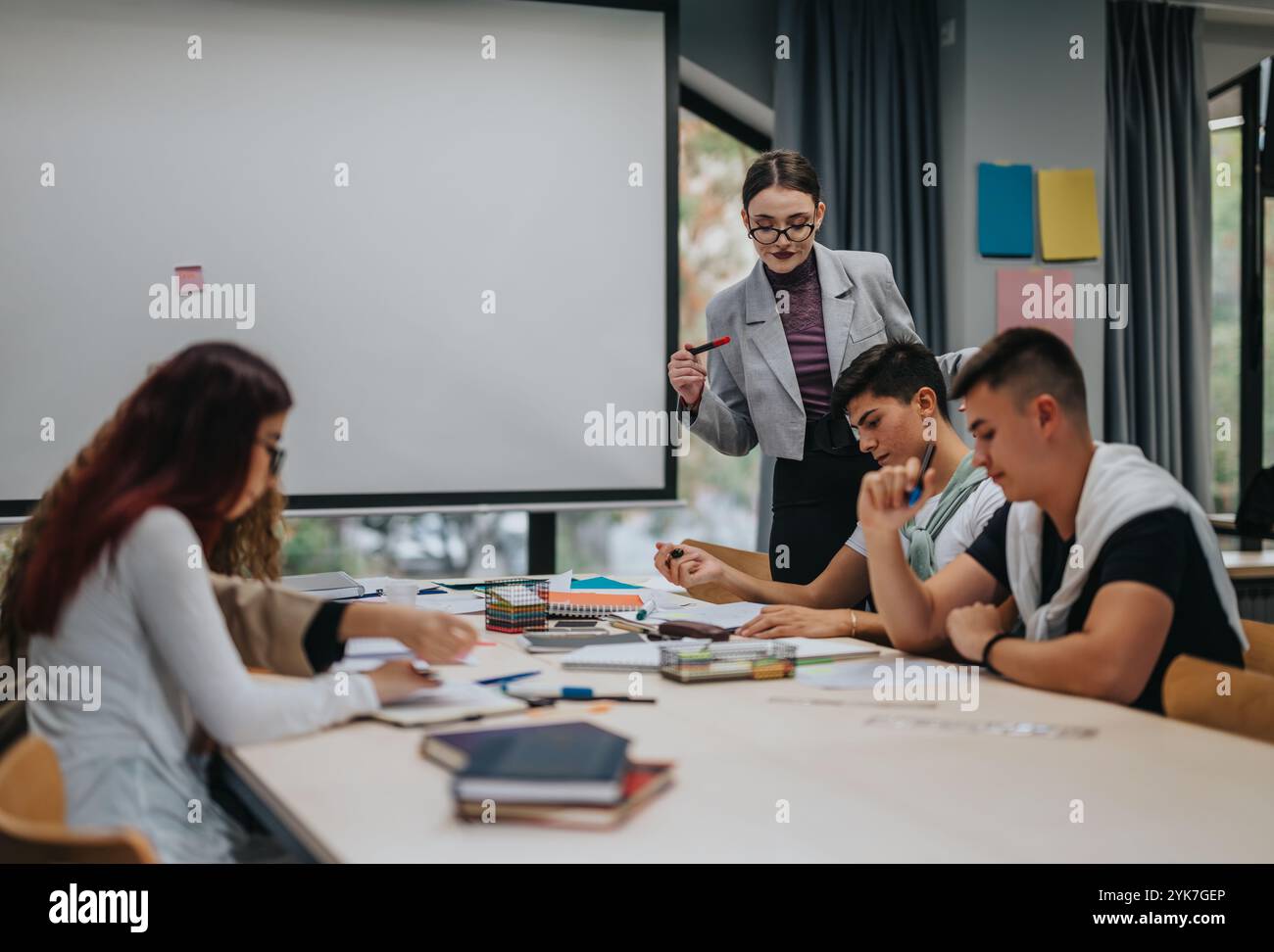 Young students collaborating with teacher in modern classroom setting Stock Photo