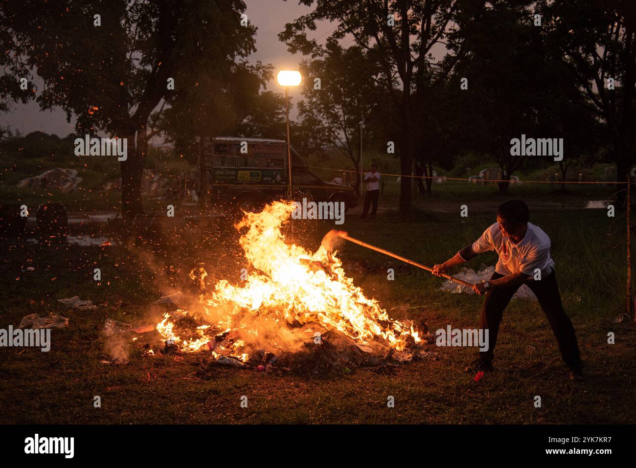 A volunteer burns joss paper in a Chinese ritual during the cemetery ...