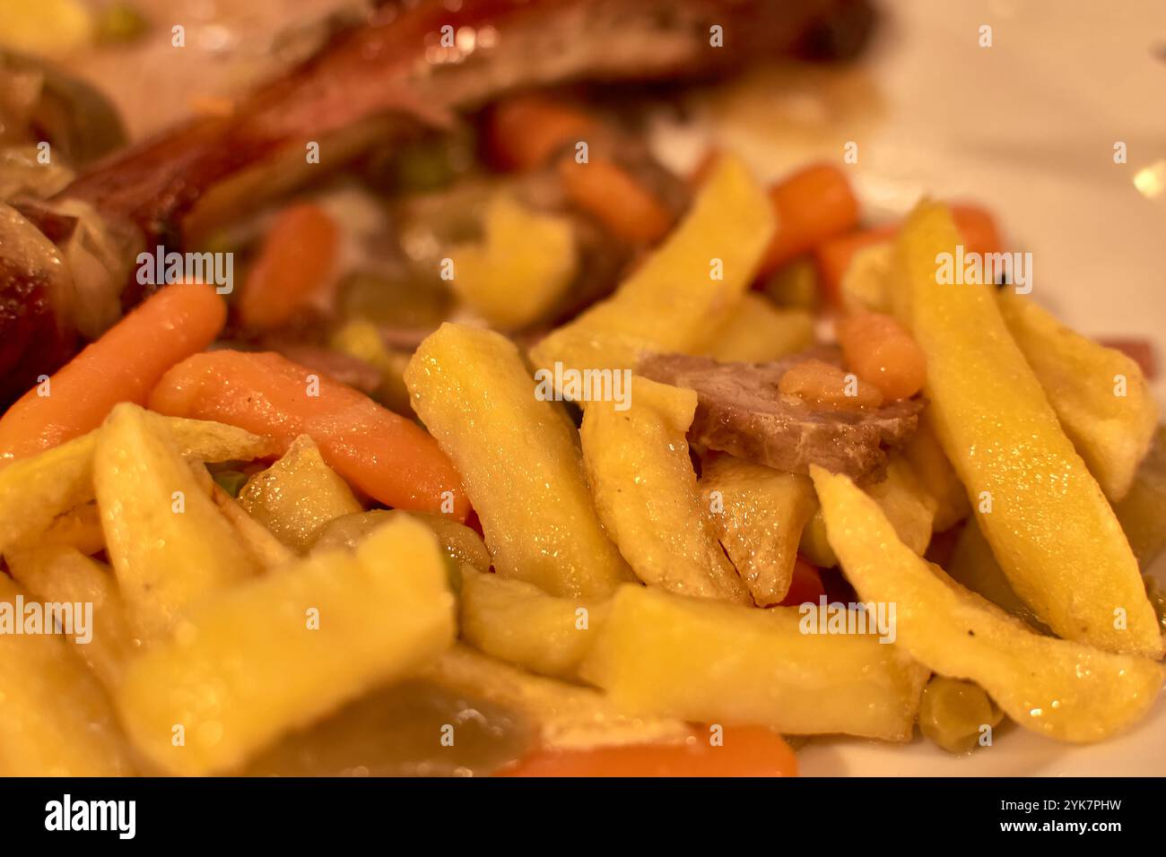 Close-up of a lamb dish garnished with golden potatoes, baby carrots, and green vegetables, beautifully plated for gourmet dining. Stock Photo