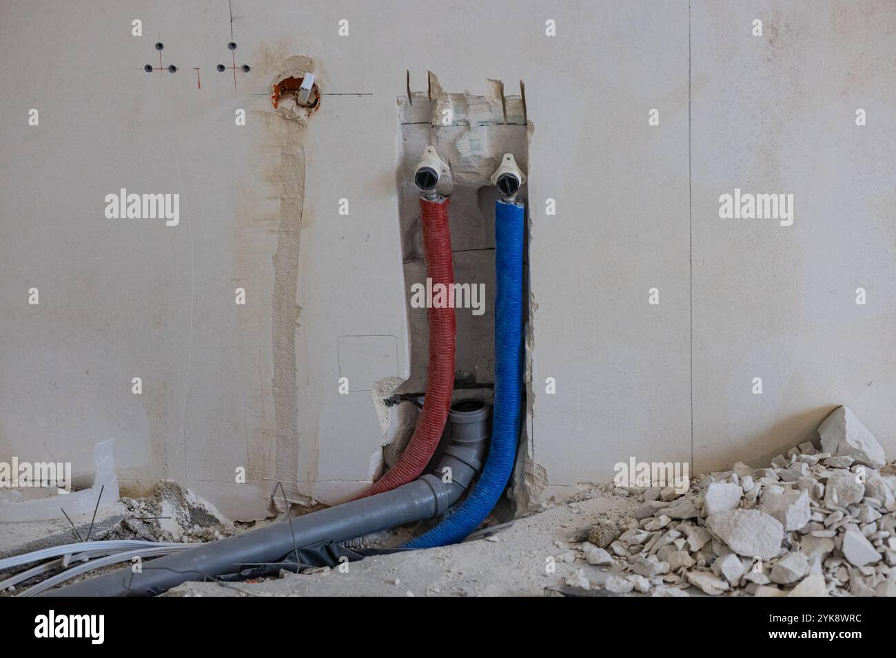 Installation of plumbing and electrical systems in a house under construction with wall fittings and scattered construction debris. Stock Photo