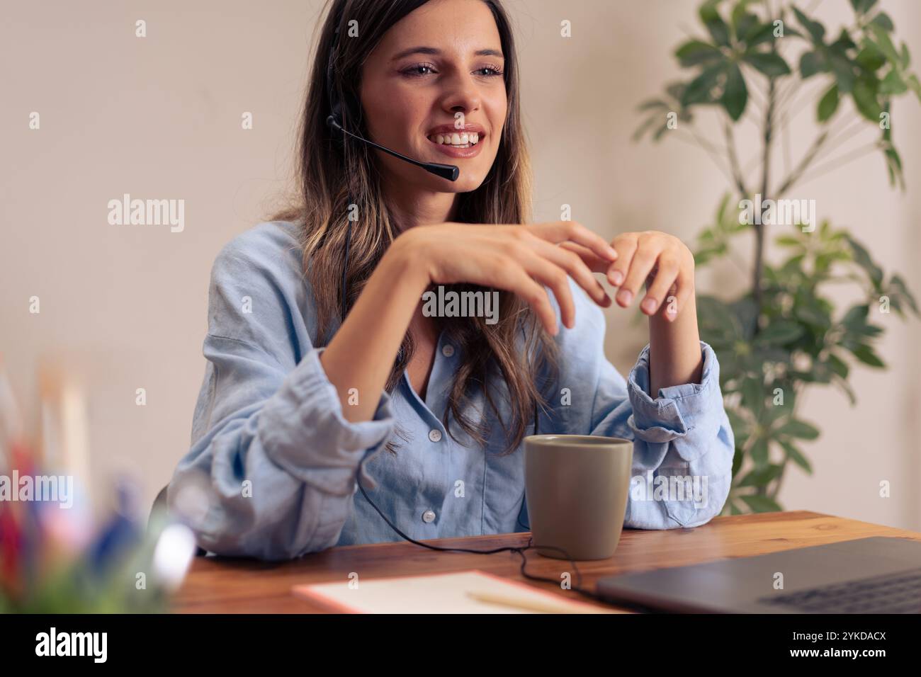 Happy female professional sharing ideas during virtual team meeting while enjoying coffee break in contemporary home office environment Stock Photo