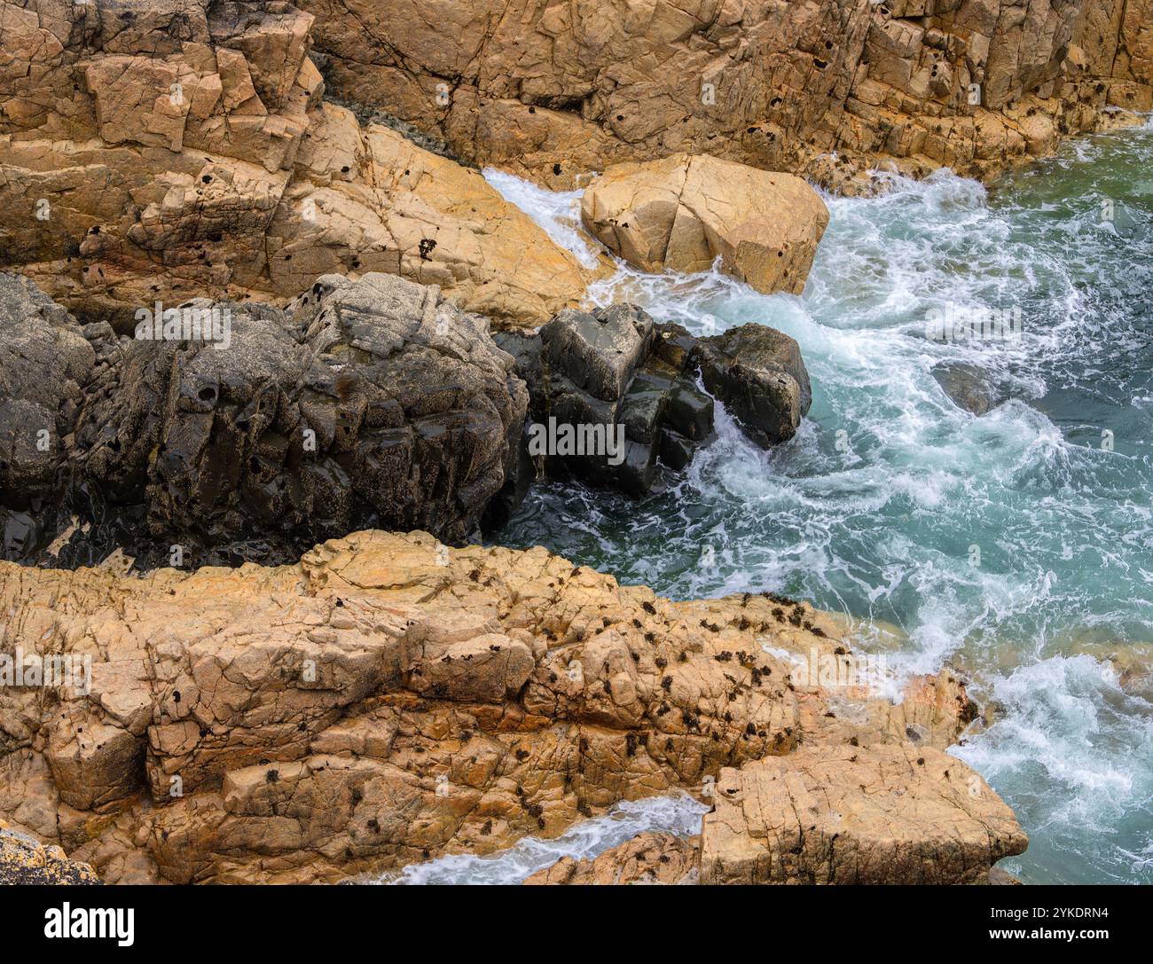 View of rocky coastline with waves crashing against the rocks. The ...