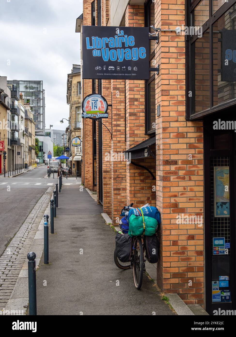 Rennes, France - July 26, 2024: A street view featuring a bicycle parked outside a bookstore named La Librairie du Voyage - Travel Bookstore. Stock Photo