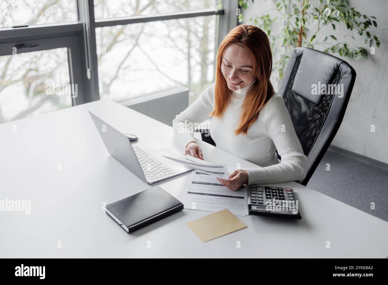 Businesswoman Analyzing Financial Documents in Modern Office Stock Photo