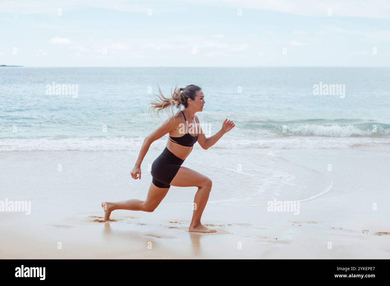 Woman doing jump squats on the beach Stock Photo