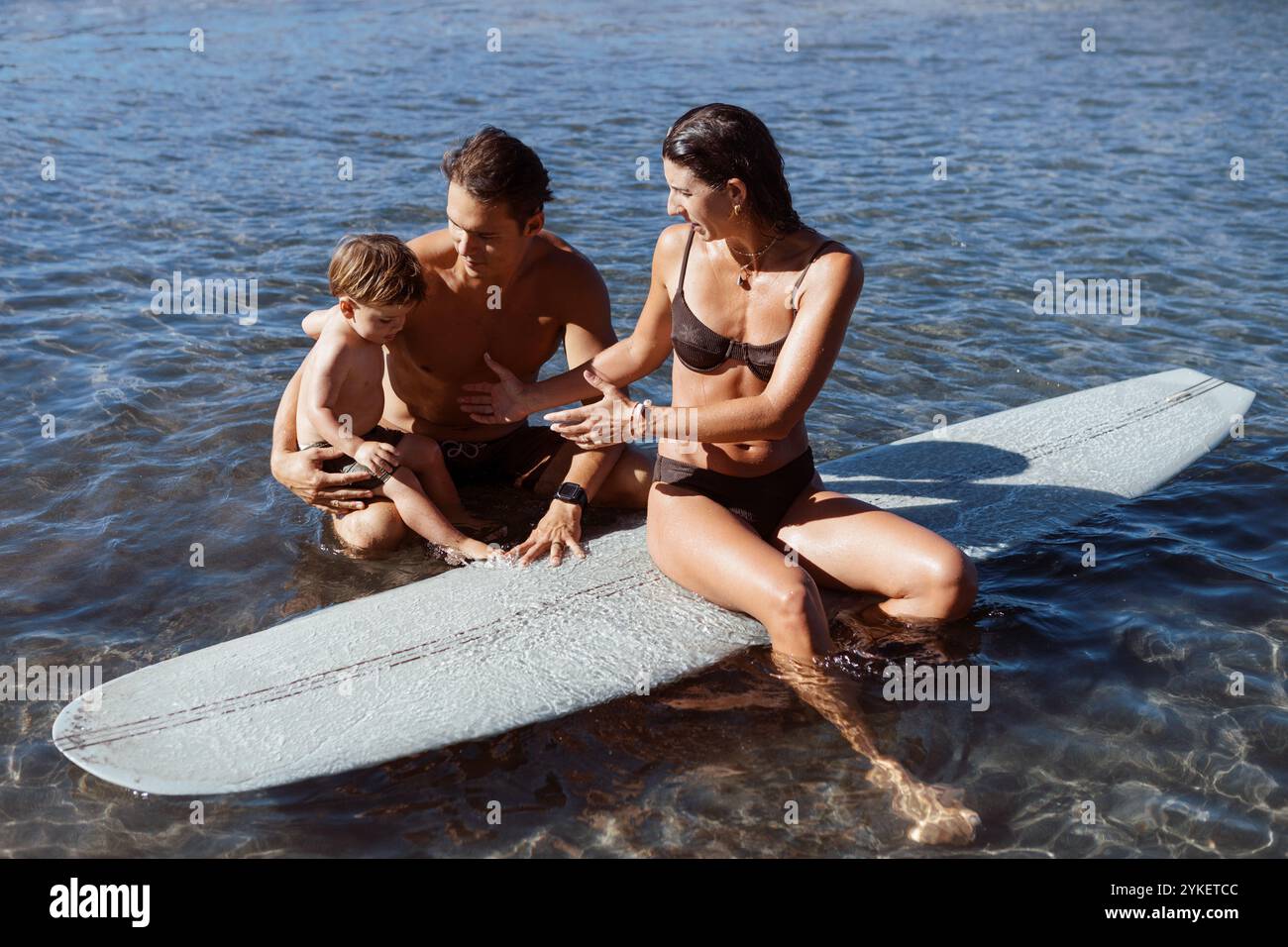 young surfer family in the ocean Stock Photo