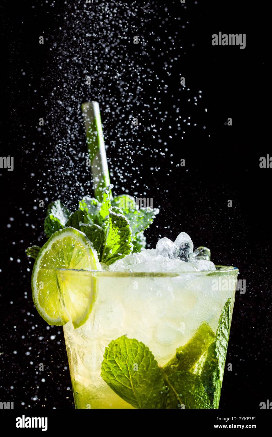 A vibrant mojito cocktail featuring fresh mint, lime slices, and ice in a tall glass Dramatic lighting highlights refreshing details, creating a livel Stock Photo
