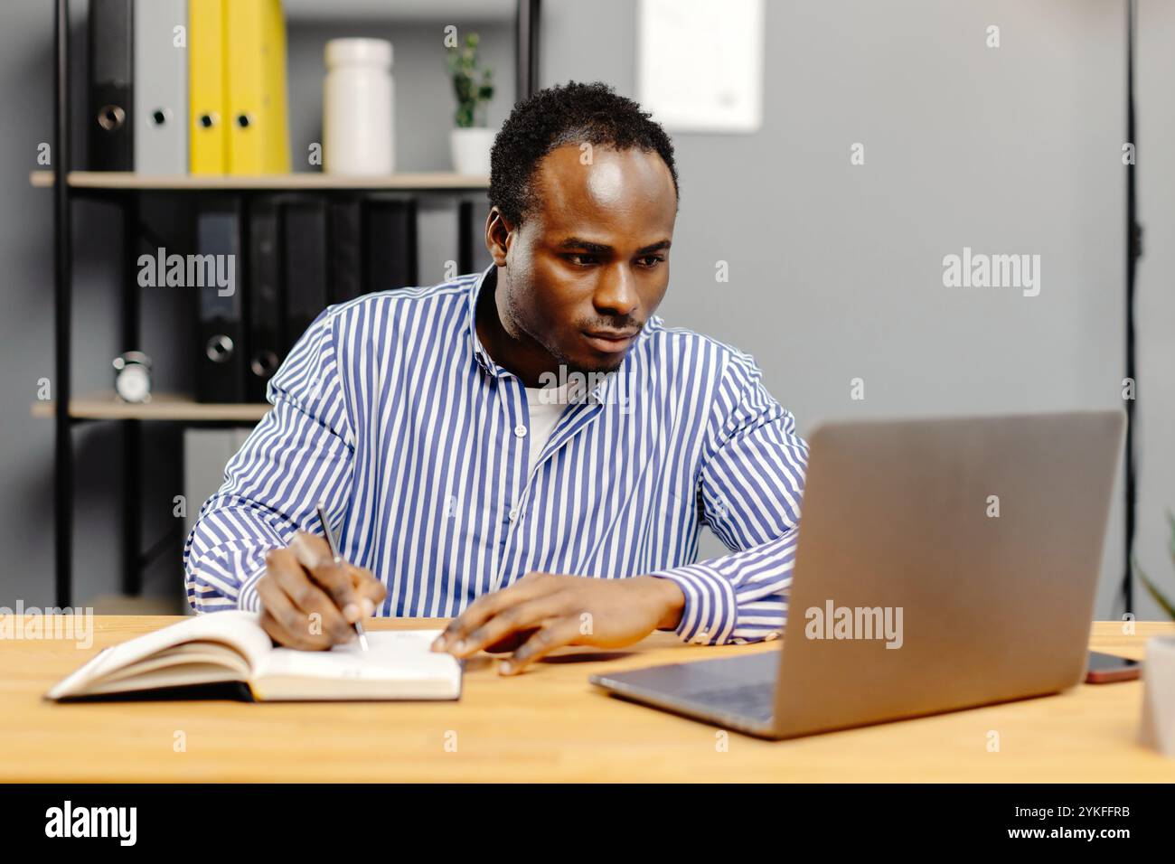 Man working on laptop at desk. Stock Photo