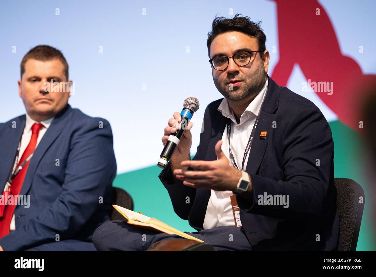 Llandudno, Wales, UK. 16th Nov 2024. Tom Hoyles, Wales & South West Political Officer for GMB Union speaks on a panel at Welsh Labour Conference. Cllr Andrew Morgan OBE is seated next to him. Sean Pursey/Alamy Live News Stock Photo