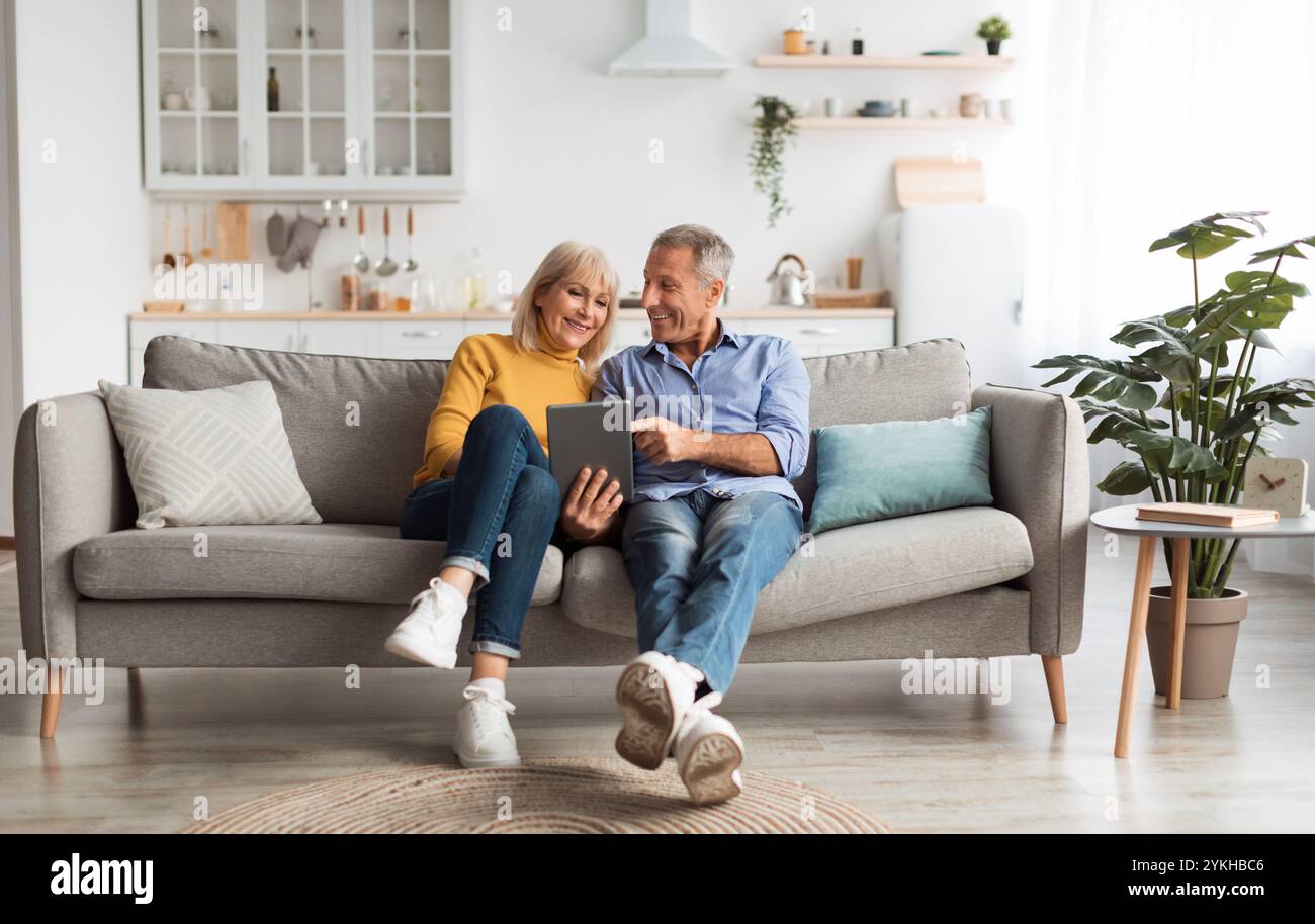 Cheerful Mature Spouses Using Digital Tablet At Home Stock Photo