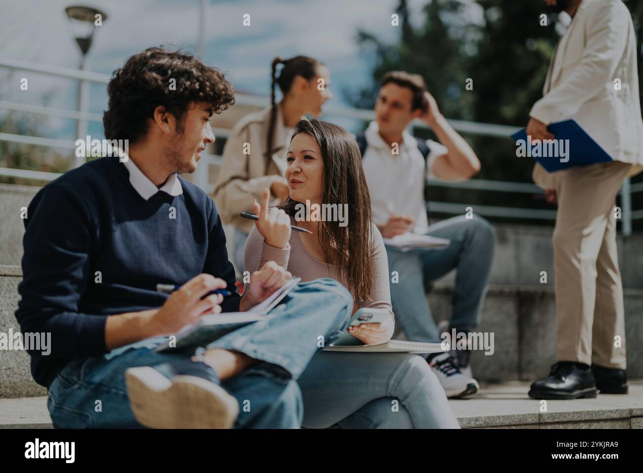 High school students collaborating outdoors with teacher assistance Stock Photo