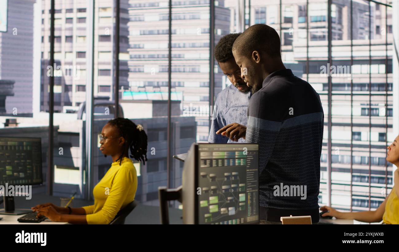 Machine learning infrastructure technicians using tablet to do checkup on algorithms that enable machines to learn from data. Coworkers in office training deep learning models using device Stock Photo