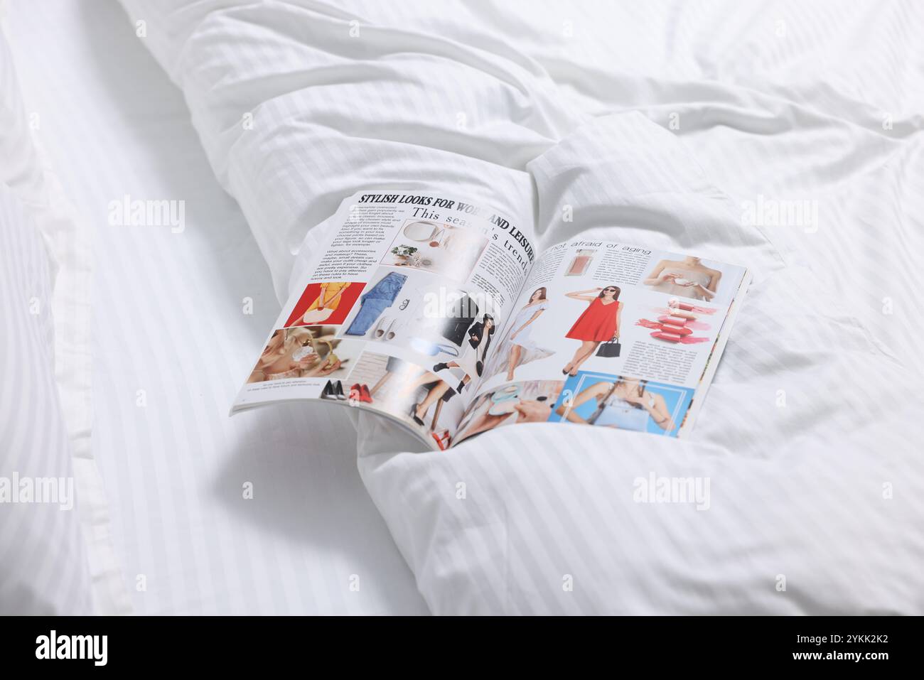 Open magazine on bed with clean linens indoors Stock Photo - Alamy
