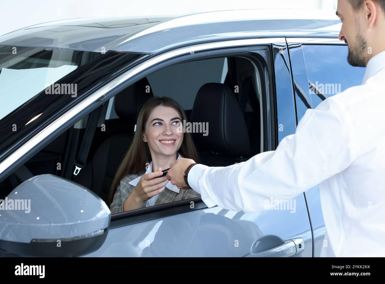 Salesman giving key to client inside new car in salon Stock Photo - Alamy