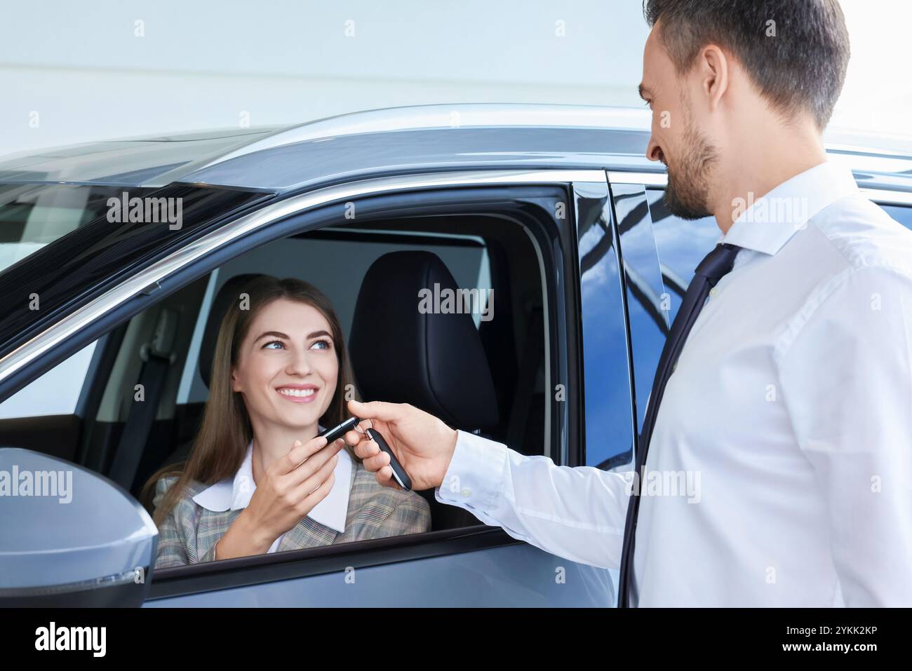 Woman giving key to man inside new car in salon Stock Photo - Alamy