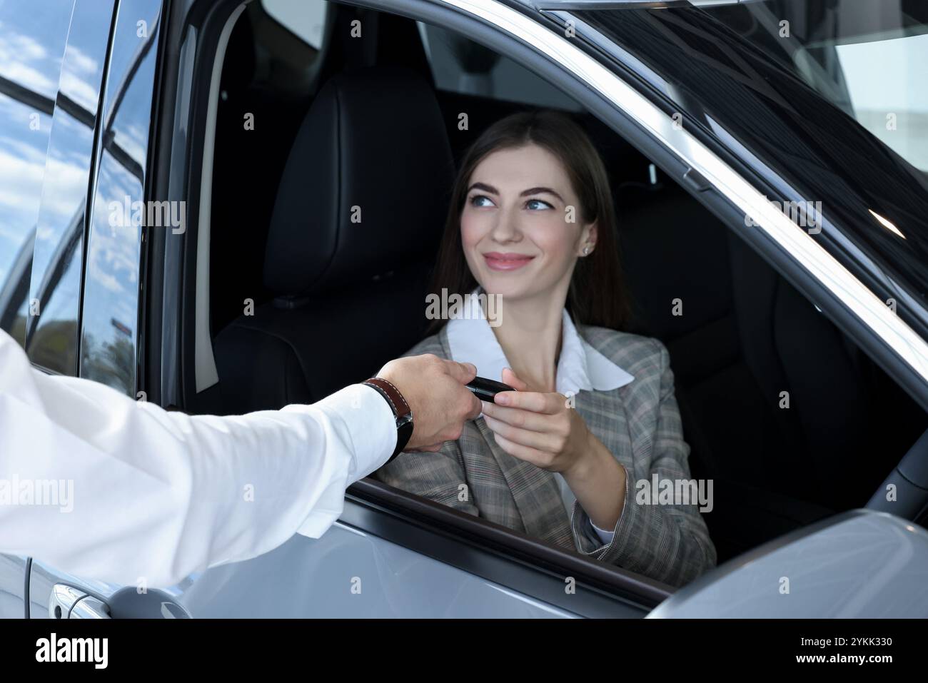 Salesman giving key to client inside new car in salon Stock Photo - Alamy