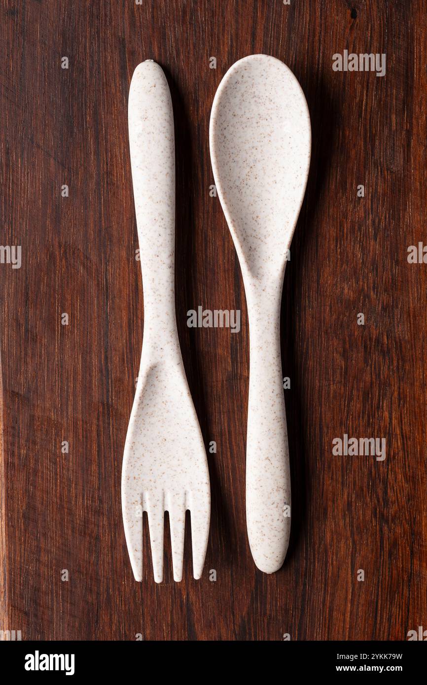 A recycled plastic spoon and fork is seen on rustic wood Stock Photo