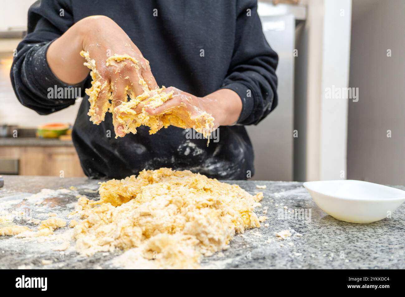 Hands of a young woman wiping off the dough that is stuck to her while preparing a pastry recipe Stock Photo