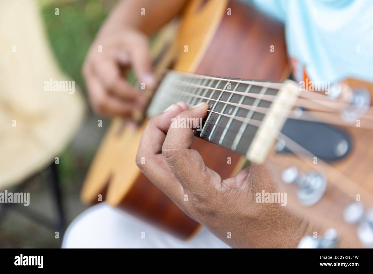 Guitar player strums the acoustic instrument, their fingers moving skillfully to create a melody filled with rhythm and notes, bringing warmth and har Stock Photo