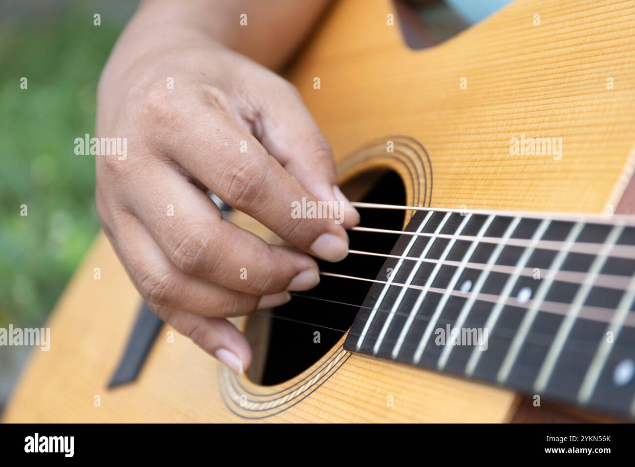 Guitar player strums the acoustic instrument, their fingers moving skillfully to create a melody filled with rhythm and notes, bringing warmth and har Stock Photo