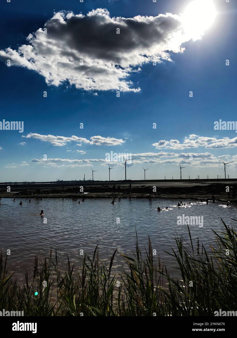 Wind Turbines and lake under a cloudy blue sky Stock Photo - Alamy