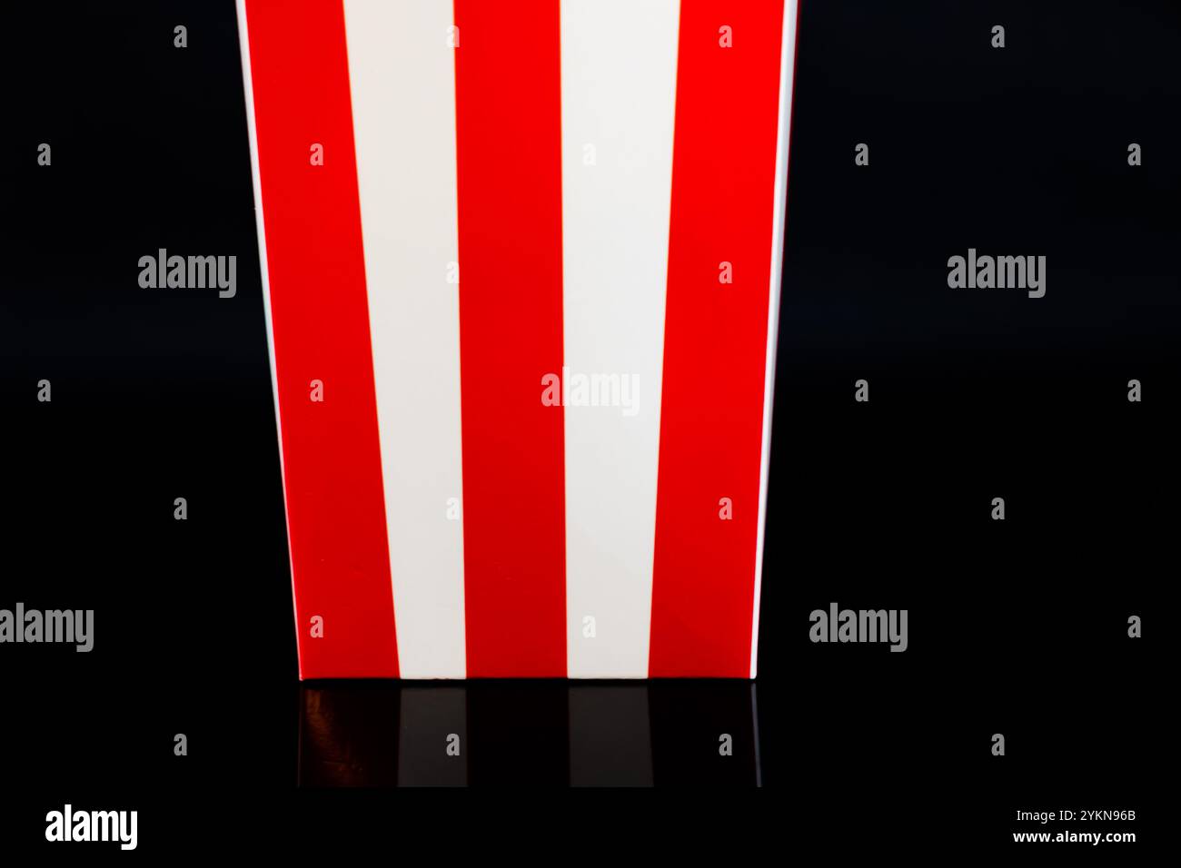 Cardboard bucket of popcorn reflected on a black background, cinema and popcorn concept Stock Photo