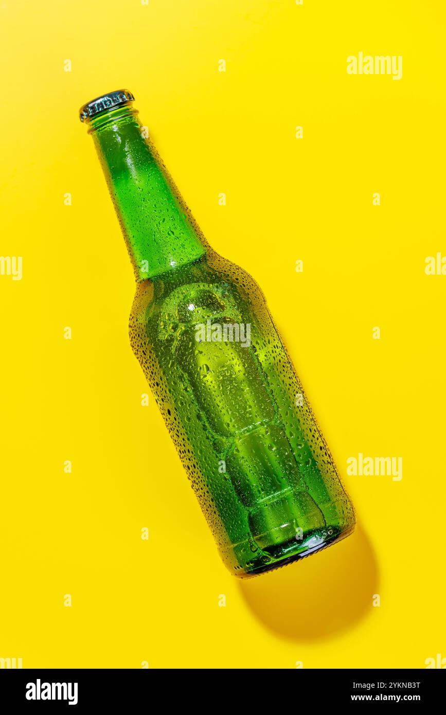 Vibrant cold beer bottle against a bright yellow background. Visible condensation, stand out sharply, creating a lively and refreshing visual appeal Stock Photo