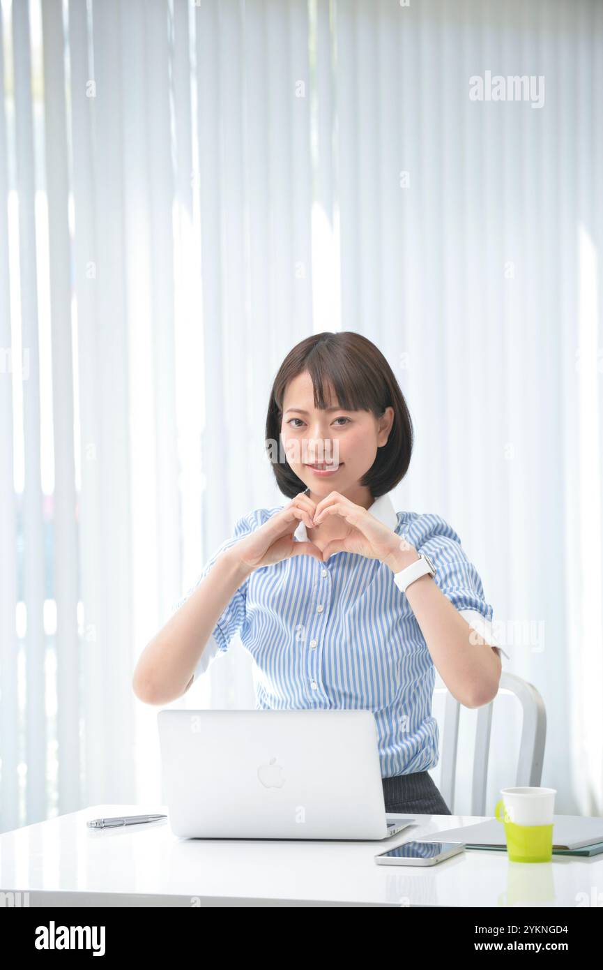 Office worker making a heart mark with her hands Stock Photo - Alamy