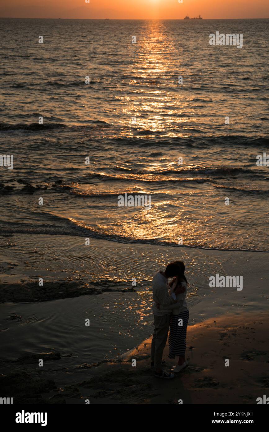 Couple kissing on the beach at sunset Stock Photo - Alamy