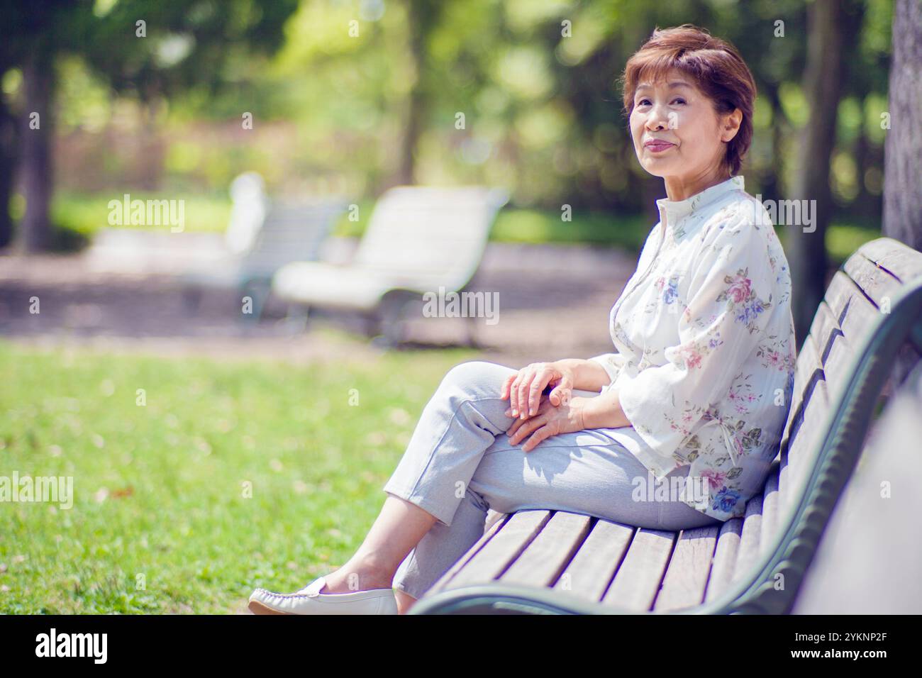 Senior woman sitting on park bench Stock Photo - Alamy