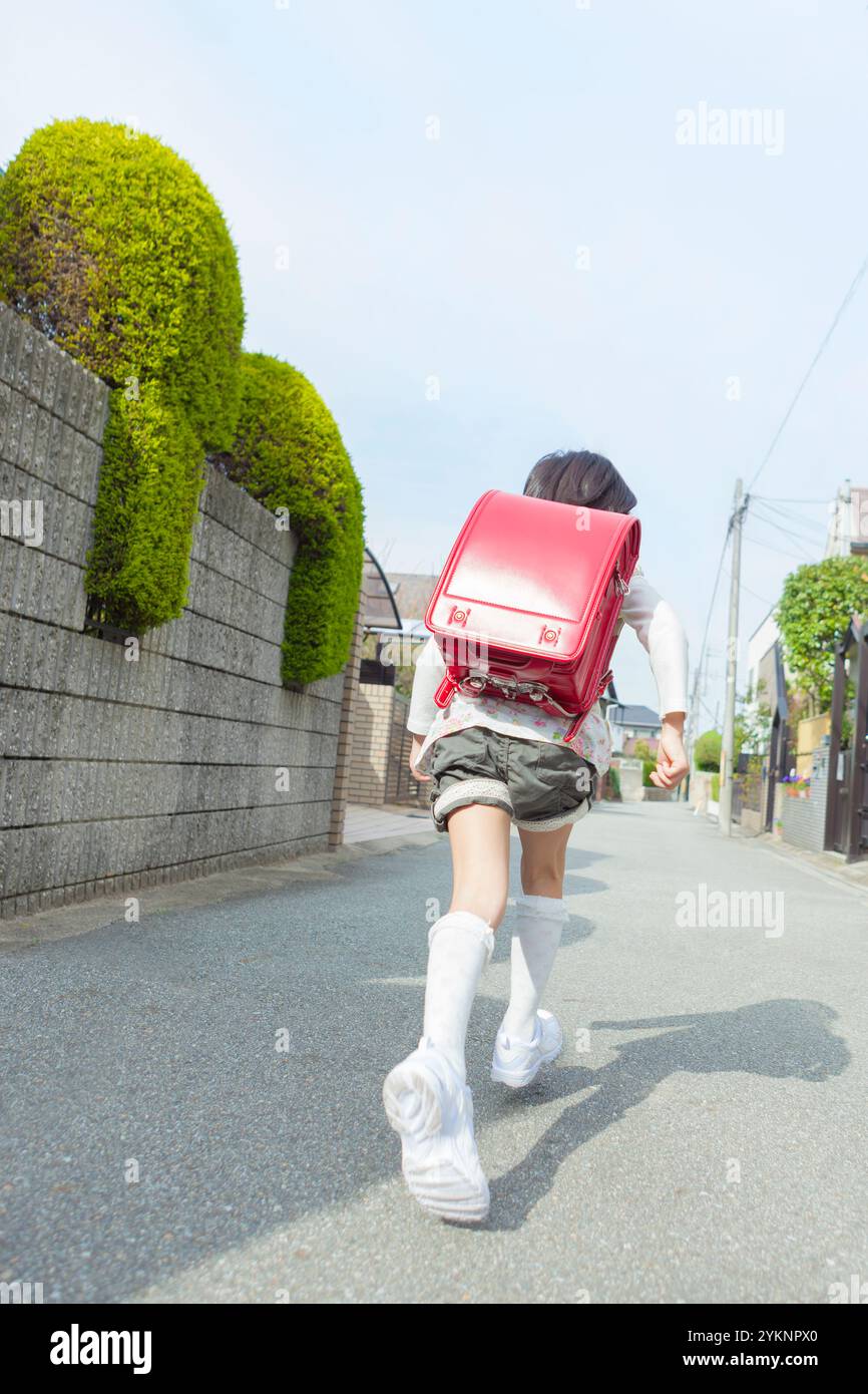 Girl running with school bag on her back Stock Photo