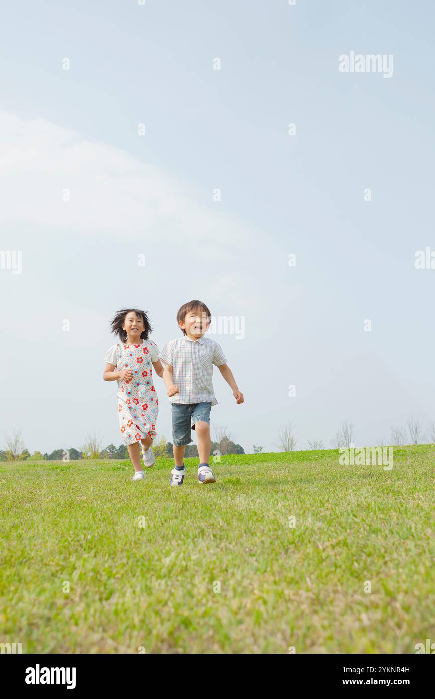 Sister and brother running in grassland Stock Photo - Alamy