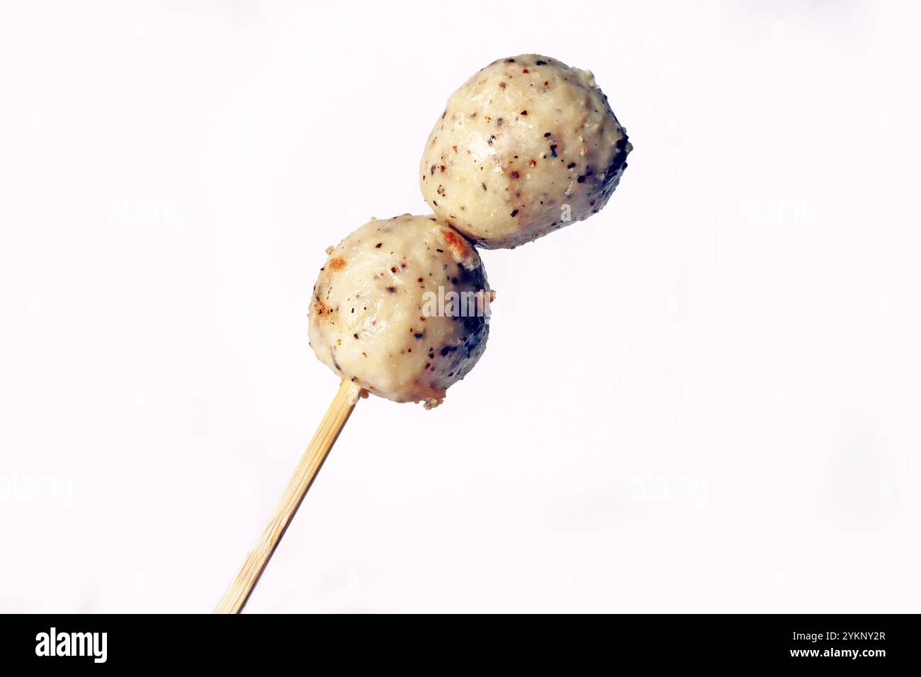 Japanese oden black pepper fish ball, chicken meatball, isolated white meatball delicious yummy. Hand holding fish ball on stick seafood street food Stock Photo