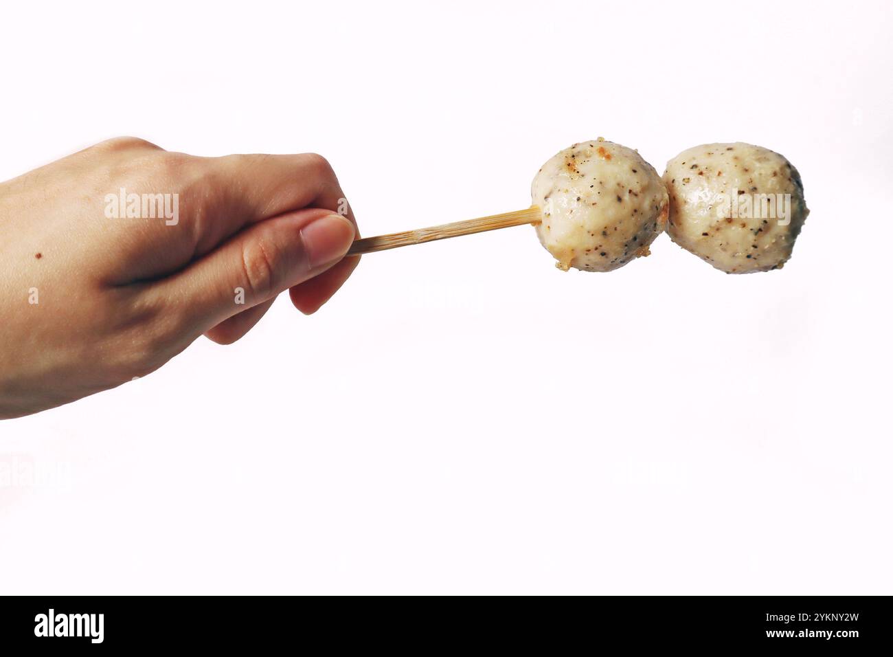 Japanese oden black pepper fish ball, chicken meatball, isolated white meatball delicious yummy. Hand holding fish ball on stick seafood street food Stock Photo