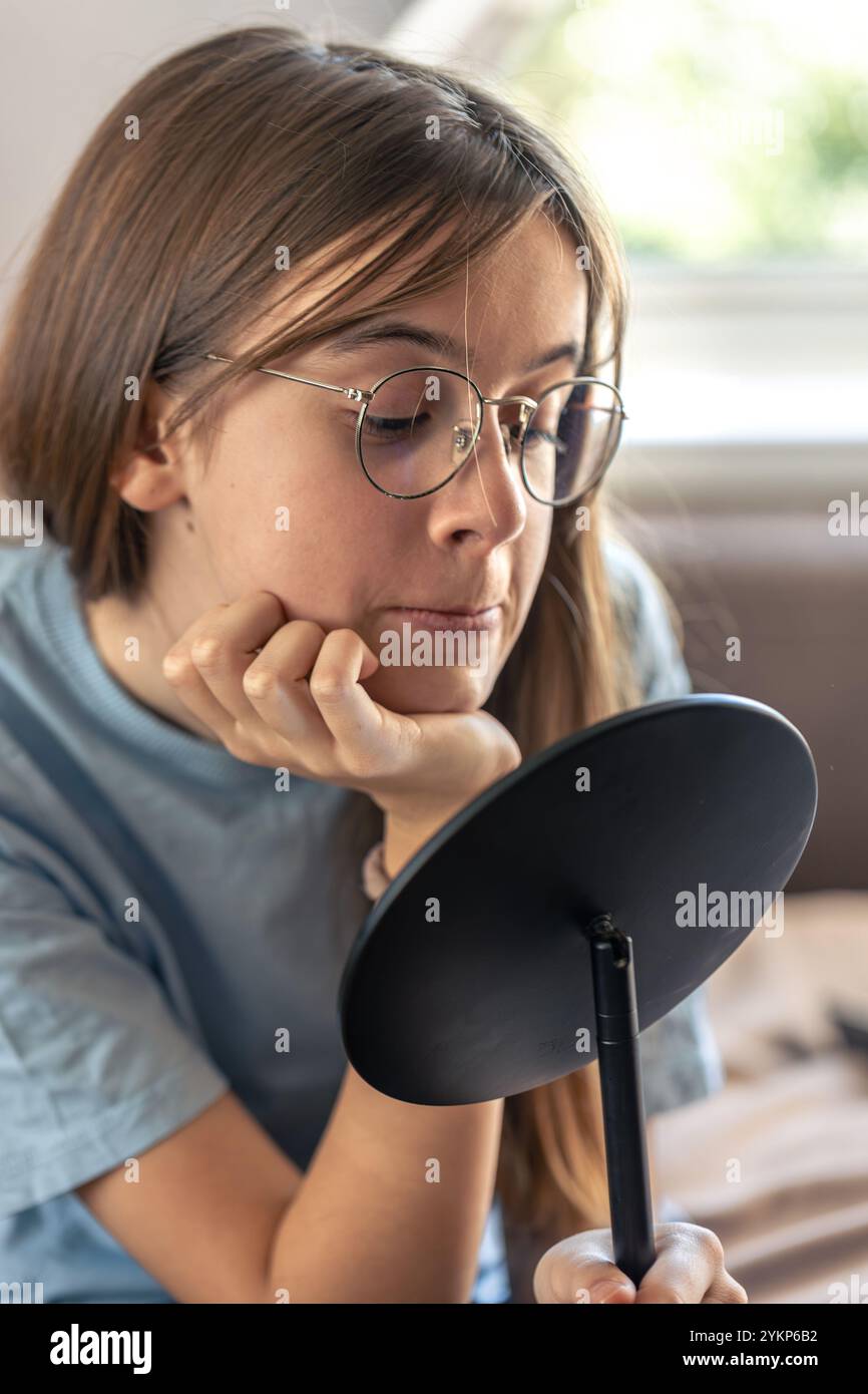Morning Routine Glasses A beautiful girl in glasses looks at herself in the mirror.Morning ...