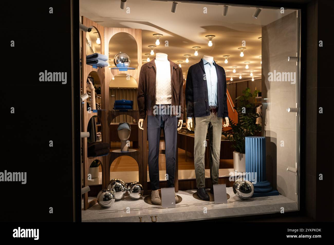 Male mannequins in store glass window display dressed casual autumn — winter elegant clothing, night scene Stock Photo