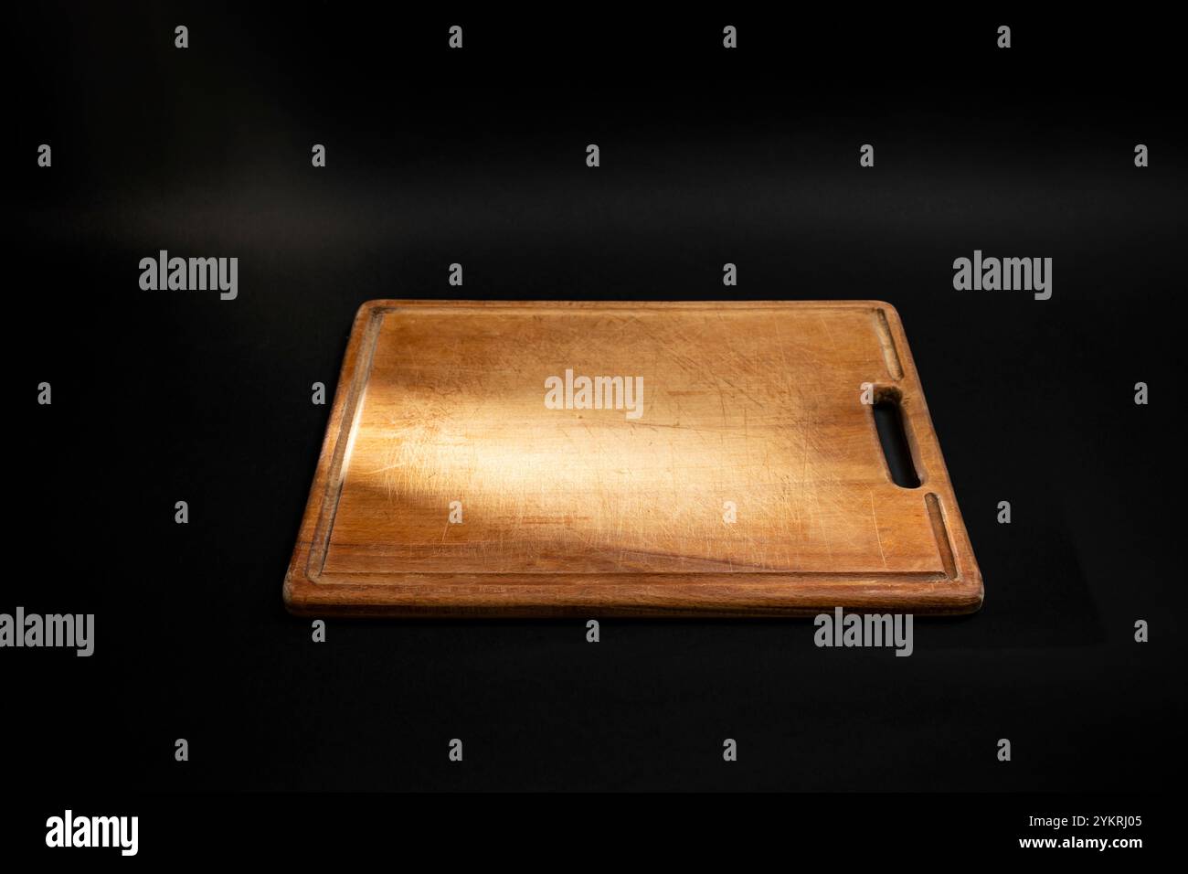 Minimal culinary backdrop with a rectangular wooden chopping board and a light ray, on black Stock Photo