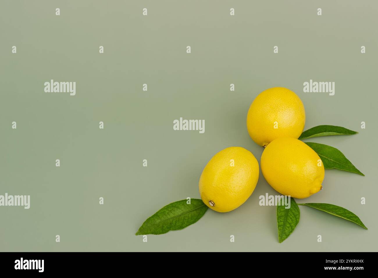 Three lemons with leaves on a green background Stock Photo