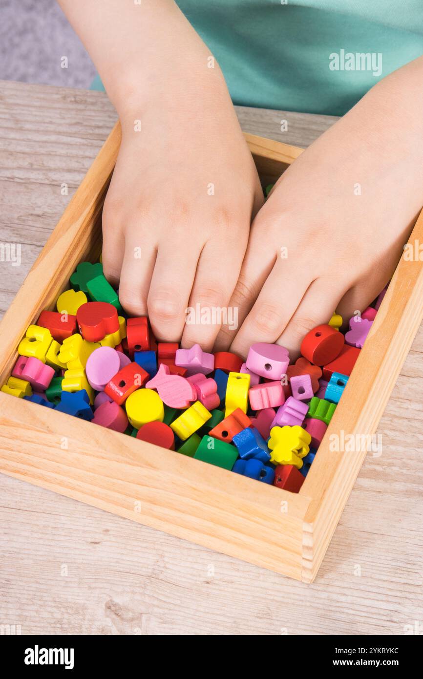 Preschooler playing thread and wooden colorful beads used to making ...