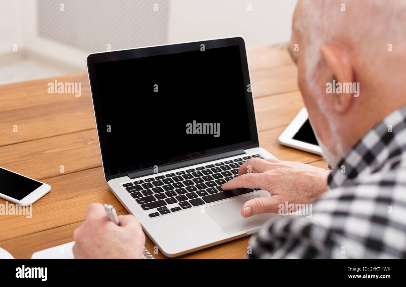 Senior man using laptop with blank screen mockup Stock Photo
